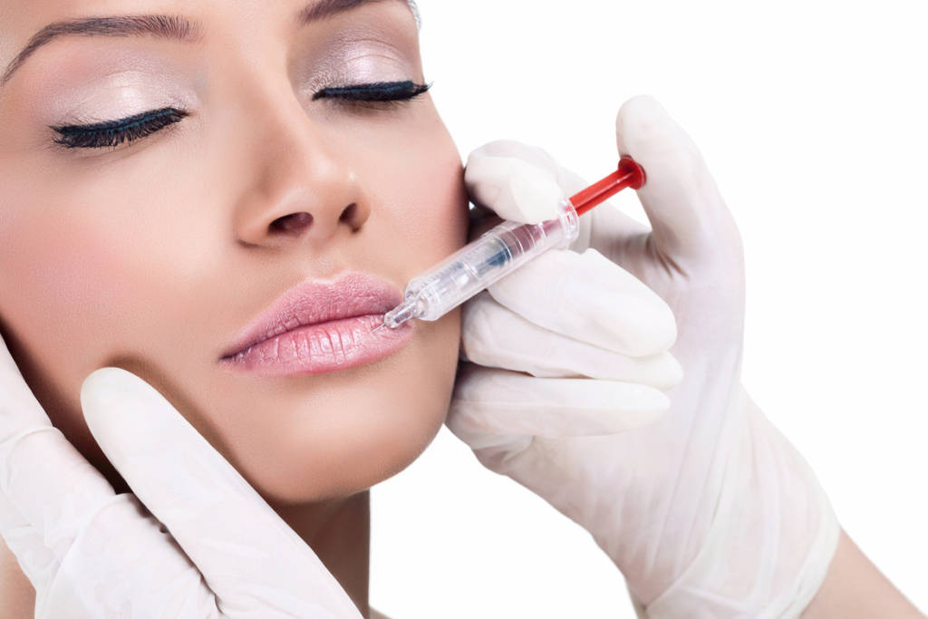 Close up of beautician hand injecting female lips with botox